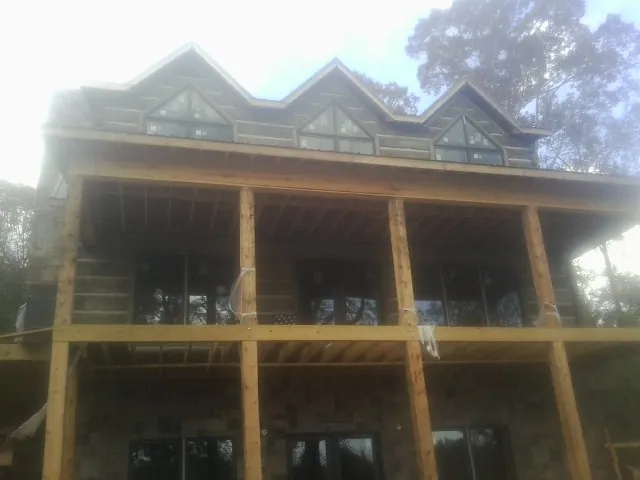 Dormers and porch framing on a large log home under construction — Roof Coating work by our crew in Griffithsville