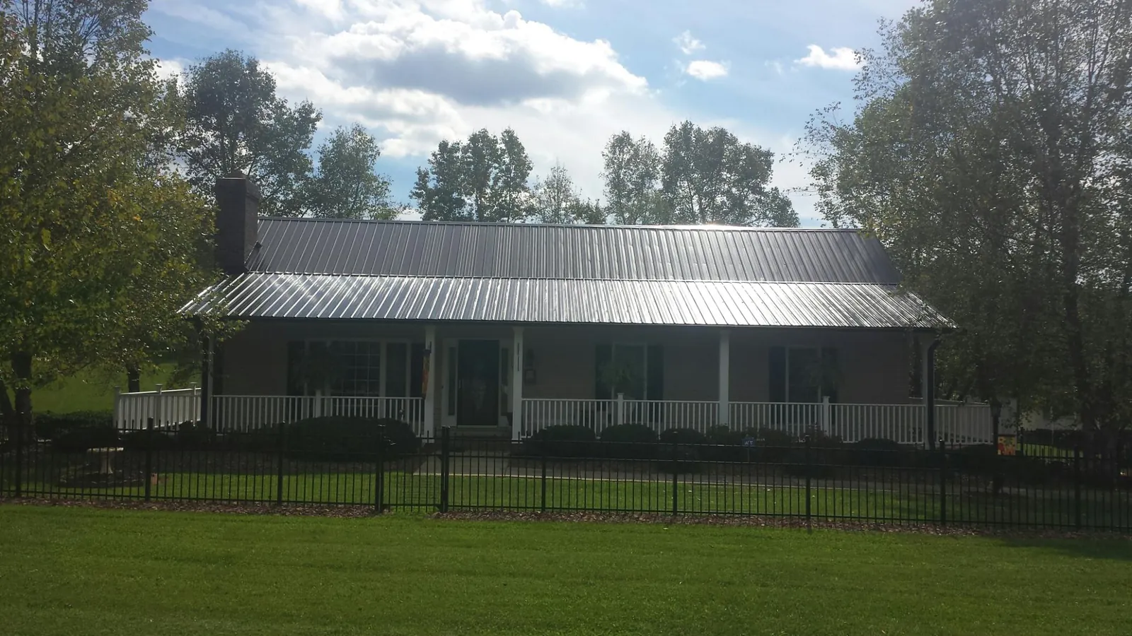 Gray metal roof on a brick ranch with a full width front porch — Gutter Guard Installation work by our crew in Griffithsville