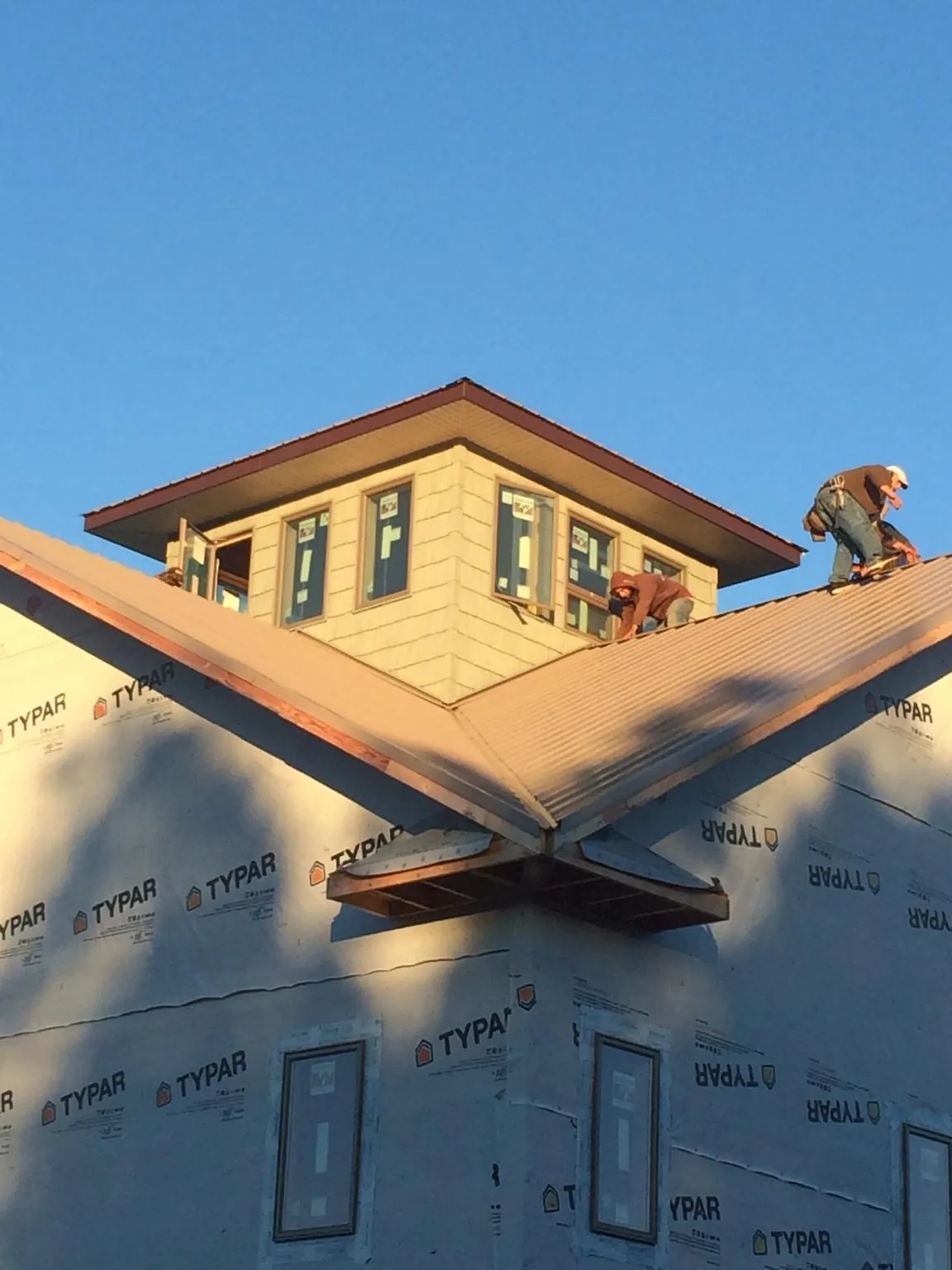 Roofers working around a rooftop cupola on a new metal roof at sunset — Roof Waterproofing in Griffithsville by Roofing Brothers